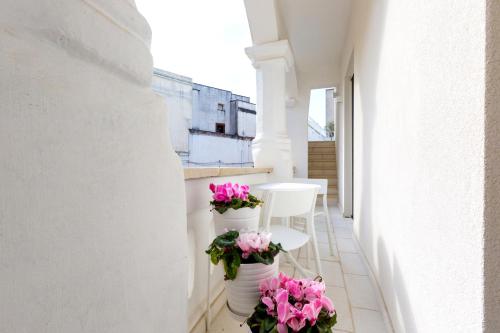 a balcony with pink flowers in white vases at La Loggetta in Ugento