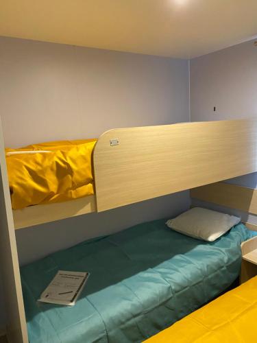Cette chambre dispose de lits superposés et d'un livre. dans l'établissement Mobil Home cosy 5 personnes proche du Puy Du Fou, à La Boissière-de-Montaigu