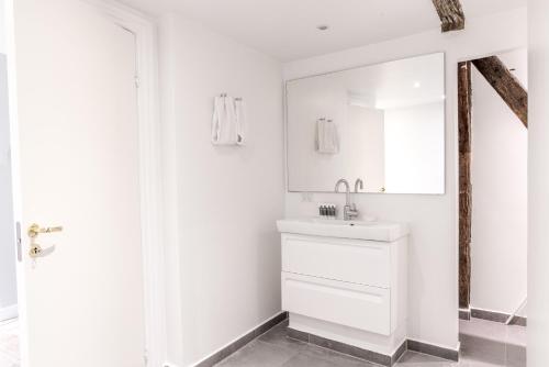 a white bathroom with a sink and a mirror at Penthouse w/rooftop terrace in latin quarter in Copenhagen
