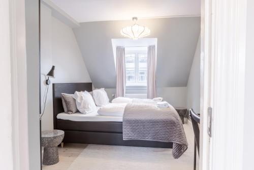 a bedroom with a bed with white sheets and a window at Penthouse w/rooftop terrace in latin quarter in Copenhagen