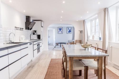a kitchen with white cabinets and a wooden table at Penthouse w/rooftop terrace in latin quarter in Copenhagen