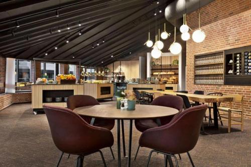 un restaurant avec des tables et des chaises et une cuisine dans l'établissement Comwell H. C. Andersen Odense Dolce by Wyndham, à Odense