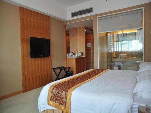 um quarto com uma cama grande e uma televisão de ecrã plano em Chang An Hotel em Shenzhen