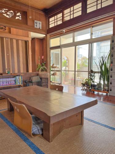 a large wooden table in a room with windows at フェーヌカジ 和室 in Miyako Island