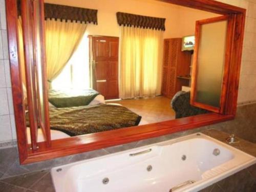 een badkamer met een grote spiegel boven een bad bij Chrismar Hotel in Riverside