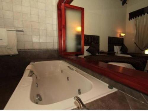 un bagno con grande vasca e specchio di Chrismar Hotel a Riverside