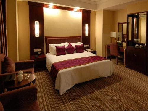 ein Hotelzimmer mit einem großen Bett mit roten Kissen in der Unterkunft Beijing Hepingli Hotel in Peking
