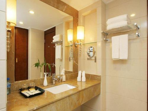 ein Bad mit einem Waschbecken und einem Spiegel in der Unterkunft Beijing Hepingli Hotel in Peking