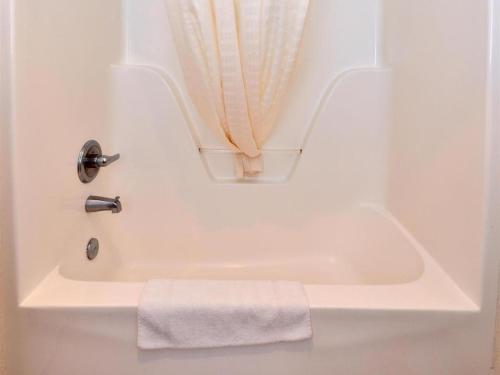 La salle de bains est pourvue d'une baignoire blanche et d'une serviette. dans l'établissement Americas Best Value Inn Smackover, 