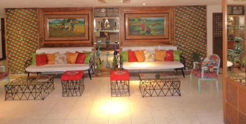Habitación con 2 sofás, sillas y mesas. en Filipiniana Hotel Calapan, en Calapan