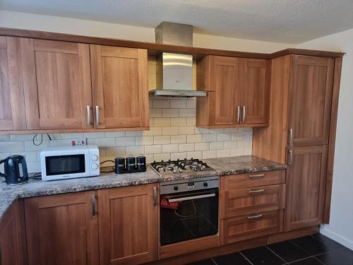 a kitchen with wooden cabinets and a stove and a microwave at Rehoboth Living in Thamesmead