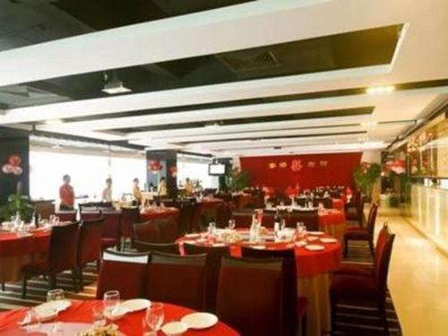 Fenghuangwei的住宿－Orient Sunseed Hotel Airport Branch，餐厅设有红色的桌椅,背景人员