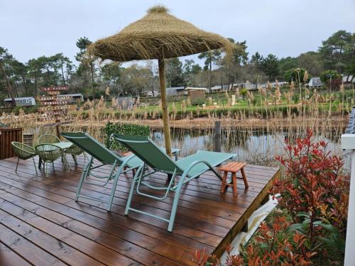 a group of chairs and an umbrella on a wooden deck at Mobil home tout confort au Camping Les Viviers, Cap Ferret in Claouey