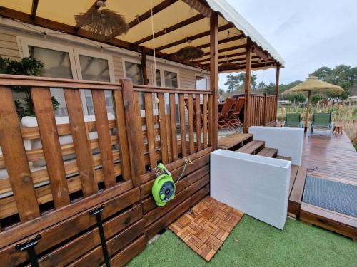 a wooden deck with a pergola and a patio at Mobil home tout confort au Camping Les Viviers, Cap Ferret in Claouey