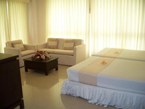 1 dormitorio con cama, sofá y mesa en Kasem Garden Hotel Surin en Ban Nong Tao