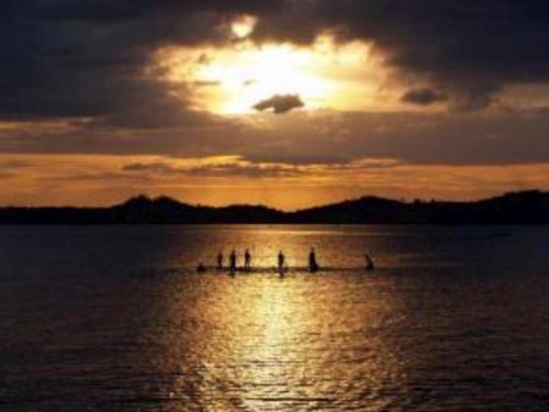 a group of people rowing in the water at sunset at Hotel Delima Sari in Parepare