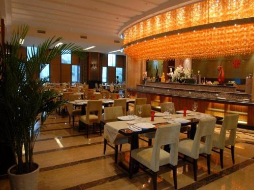 ShuangliuにあるSichuan Tennis International Hotel Main Buildingのテーブルと椅子、大きなシャンデリアのあるレストラン