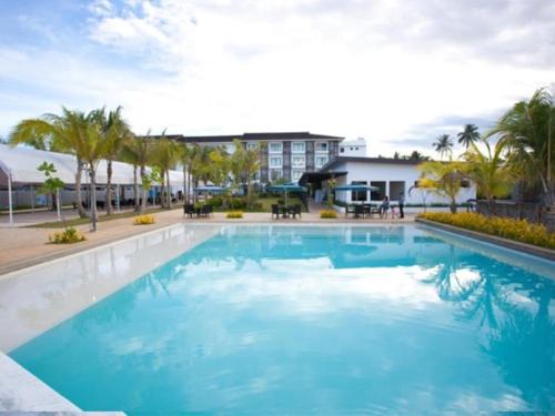 duży niebieski basen z palmami i budynek w obiekcie Ciriaco Hotel w Calbayog