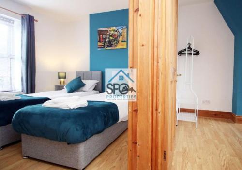 Spacious 3BR Home-6 Guests-Business-Families-Netflix-Free Parking & WiFi في Pontnewynydd: غرفة نوم بسريرين وجدار ازرق