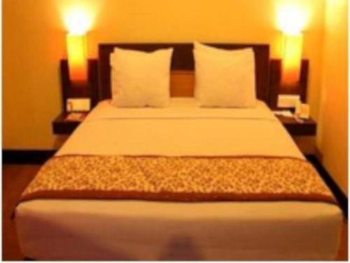 uma cama grande num quarto de hotel com duas lâmpadas em Abadi Hotel Sarolangun by Tritama Hospitality em Sarolangun