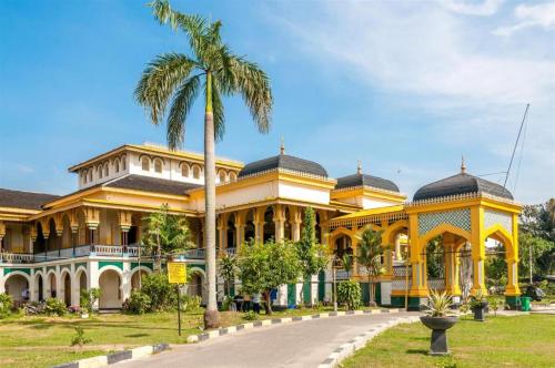 un grande edificio giallo con una palma di fronte di Danau Toba Hotel International a Medan