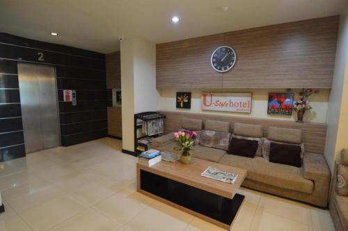 a living room with a couch and a clock on the wall at U Style Hotel in Ban Phang Khwang Tai