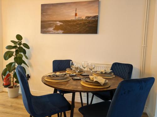 uma mesa de jantar com cadeiras e uma mesa com copos de vinho em Blue Horizon Holiday Cottage - 4 Minute Walk to the Beach em Weymouth