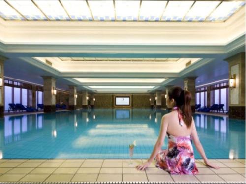a woman sitting in front of a swimming pool at Changzhou Fudu Qingfeng Garden Hotel in Beigang