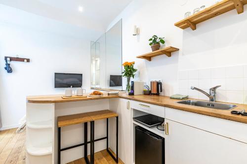 une cuisine avec des armoires blanches et un évier dans l'établissement PARIS 3° CENTRE MARAIS -COCON CALME (PROPRETÉ +++), à Paris