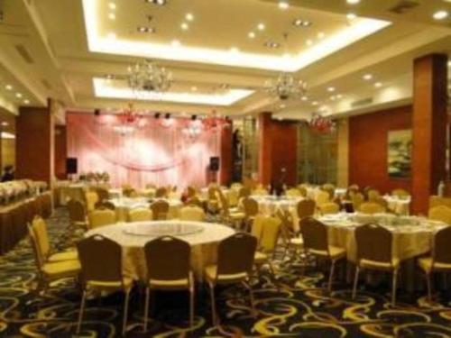 - une salle de banquet avec des tables, des chaises et une scène dans l'établissement Zhoushan Changzheng Spring Hotel, à Liangmaotou