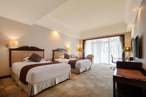 una camera d'albergo con due letti e una televisione di Country Garden Phoenix Hotel Xianning a Wenquanzhen