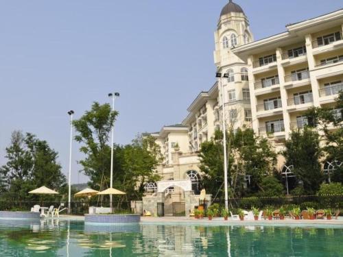 un edificio con una piscina d'acqua di fronte a un edificio di Country Garden Phoenix Hotel Xianning a Wenquanzhen