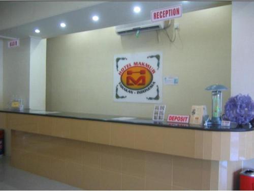 a waiting room with a counter with a sign on the wall at Hotel Makmur in Karanganyar