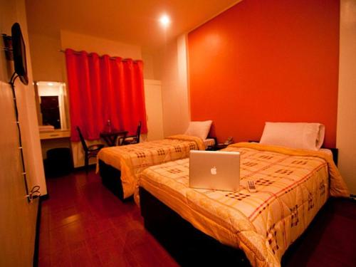 a hotel room with two beds with a laptop on the bed at Asog County Hotel in Iriga City