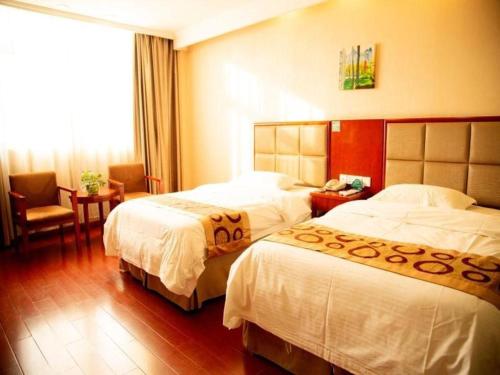 a hotel room with two beds and a chair at GreenTree Inn Bozhou Weiwu Road Hotel in Bozhou