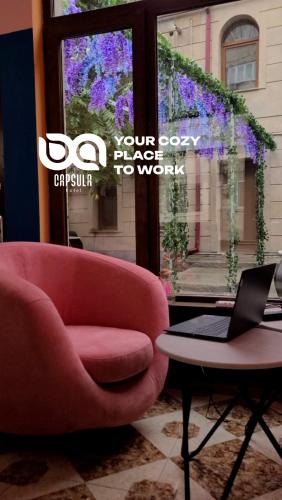 a red chair sitting next to a table with a laptop at Capsula hotel in Yerevan