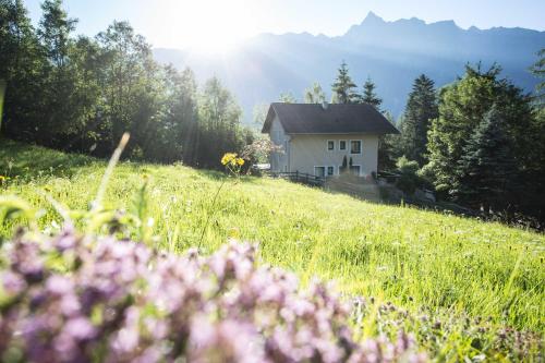 ein Haus auf einem Hügel mit einem Blumenfeld in der Unterkunft Aktiv-Ferienwohnungen Pienz-Bobnar in Sautens
