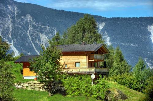a house on a hill with mountains in the background at Aktiv-Ferienwohnungen Pienz-Bobnar in Sautens