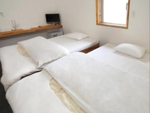 3 weiße Betten in einem Zimmer mit Fenster in der Unterkunft Business Hotel Tsuwano in Tsuwano