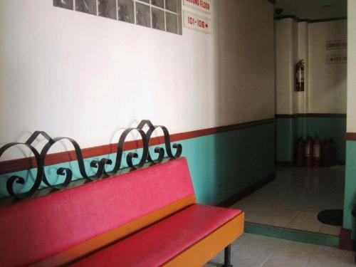 a red bench in a room with a wall at Magayon Hotel in Buenavista