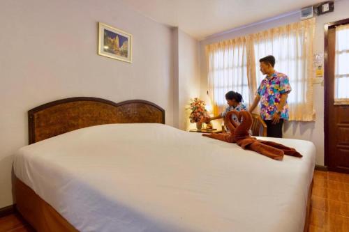 un hombre y un niño parados junto a una cama en Cha Am Villa Beach en Ban Sahakham