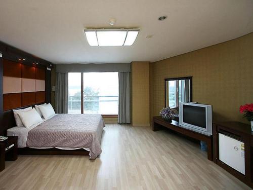 um quarto com uma cama e uma televisão de ecrã plano em Goodstay Soo Hotel em Gangneung