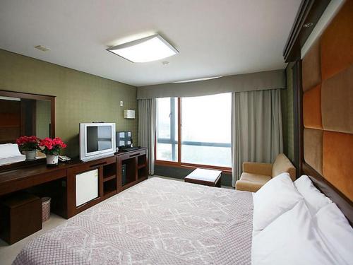 a hotel room with a bed and a television at Goodstay Soo Hotel in Gangneung