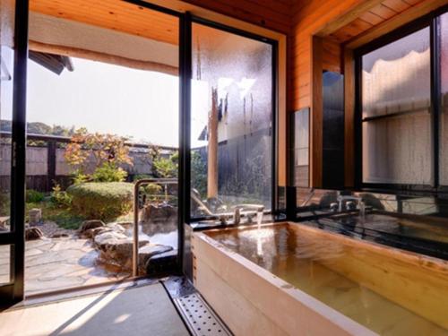 a bathroom with a bath tub with a large window at Nanaironoyu Hotel in Takeo