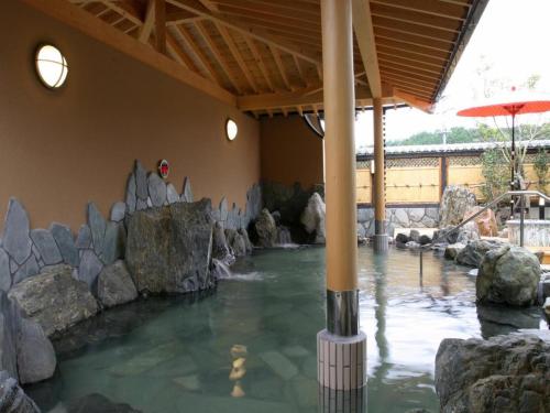 uma piscina de água com pedras numa casa em Nanaironoyu Hotel em Takeo