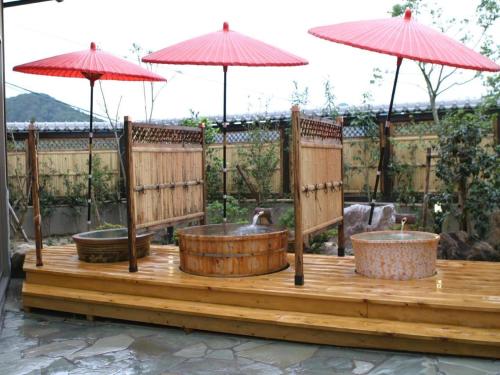 a wooden deck with three bowls and two umbrellas at Nanaironoyu Hotel in Takeo