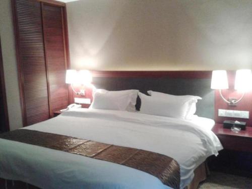 uma cama grande num quarto de hotel com duas lâmpadas em Guangna Hotel em Huizhou