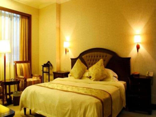 a bedroom with a large bed with white sheets and pillows at Quanzhou Royal Prince Hotel in Quanzhou