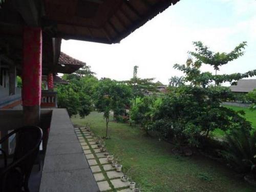 a porch of a house with a yard with trees at Bali Bagus Hotel in Lovina