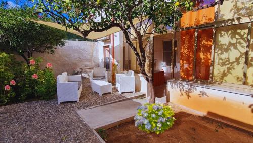 a group of white chairs and a tree in front of a building at Guest House San Vito Lo Capo in San Vito lo Capo